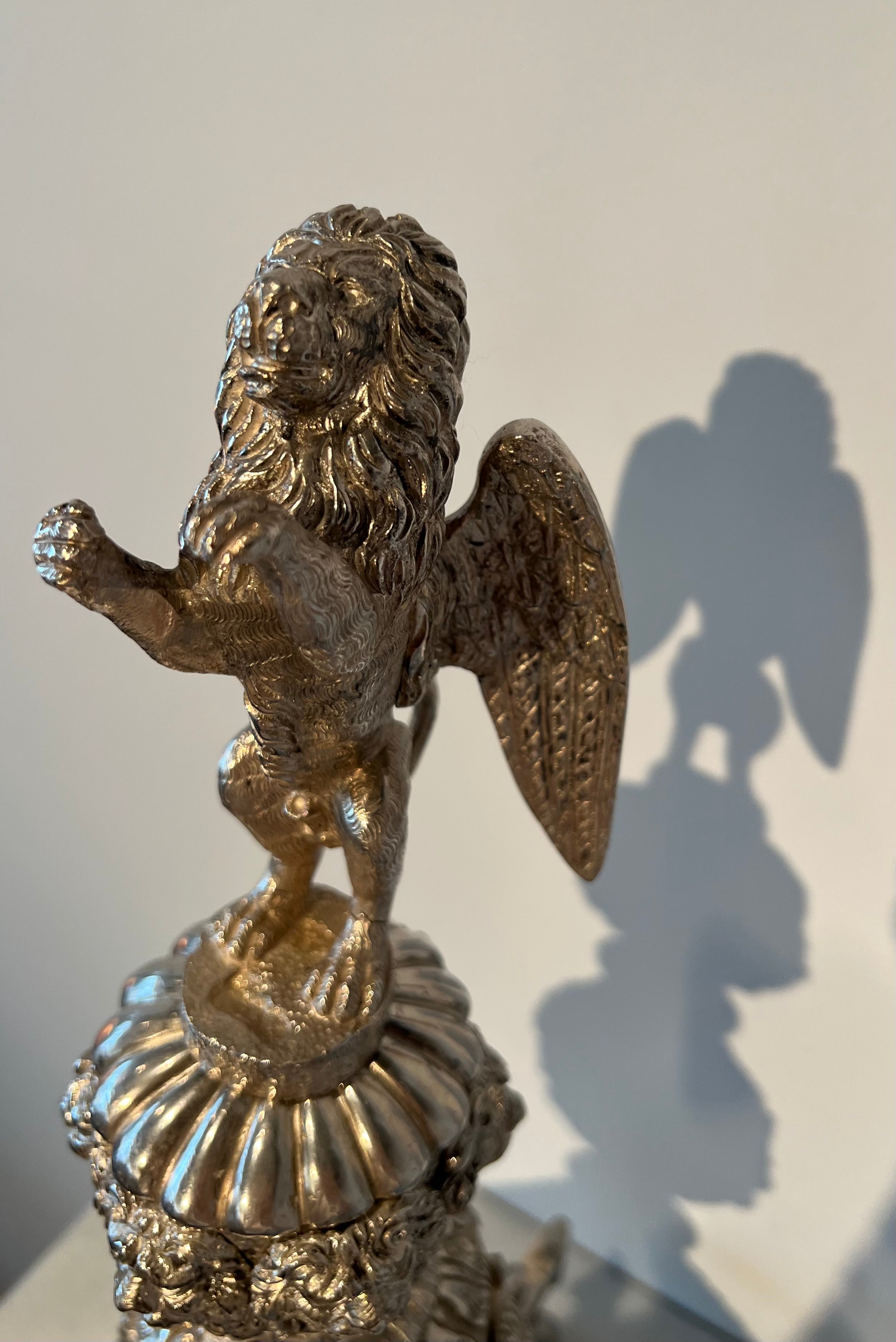 Paar monumentale zilveren andirons met gevleugelde leeuwen